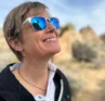 Photo of Molly Booker wearing sunglasses, looking up and smiling